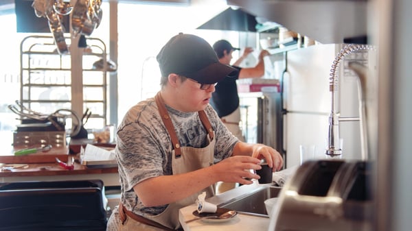 A man cleans dishes inside the kitchen of a small business.