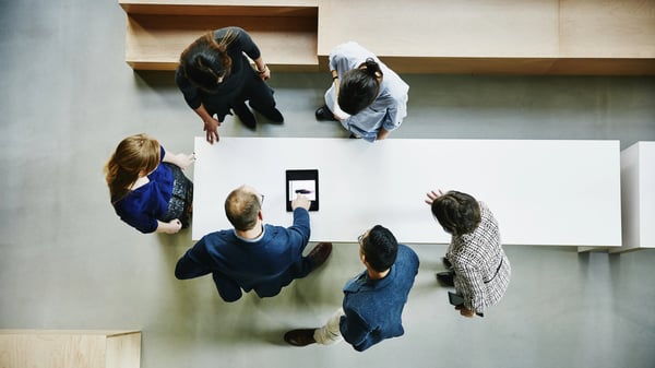 Photograph with birds eye view of office workers around a table working together